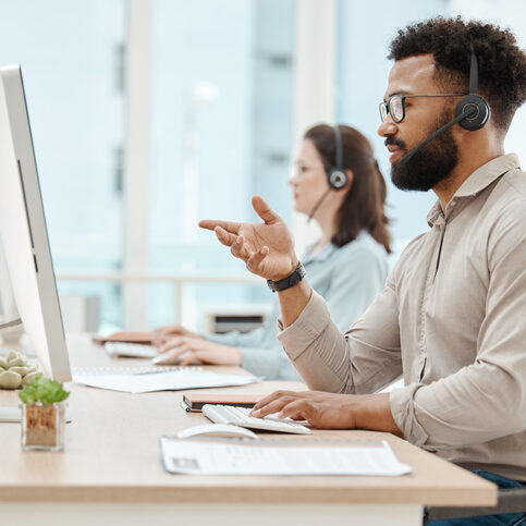 Black man, customer support service office and working for online call center internet telemarketing business. Crm consultant at desk, helping client and consulting computer software for advice Black man, customer support service office and working for online call center internet telemarketing business. Crm consultant at desk, helping client and consulting computer ai software for solution